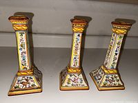 Three hand painted Portuguese ceramic candlesticks with floral and deer motifs.