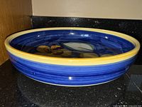 Large blue serving bowl with yellow rim and floral design inside