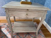 Full front view of the side table showing drawer closed with carved leg details and lower shelf.