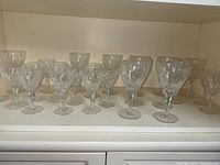 Full view of 24 crystal glasses with 12 large and 12 small glasses arranged in two rows.