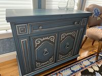 Overall front view with top closed showing painted blue bar cabinet with decorative hardware and molding