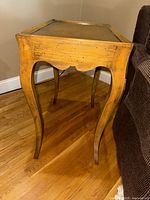Angled view of one wooden side table showing tabletop, apron, and curved legs