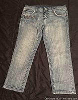 Front view of lightly faded blue denim jeans showing front pockets, coin pocket, button closure and zipper fly.