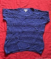 Photo of first Calvin Klein knit top flat laid, showing detailed knit pattern and ribbed edges