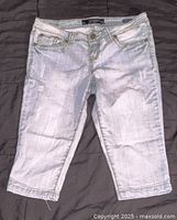 Front view of light wash denim capri jeans by Jessica Simpson, size 30, showing slight distressing and button closure.