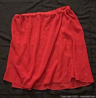 Red semi-sheer skirt with elastic waist laid flat on dark background.