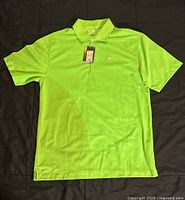 Front view of bright green Nike polo shirt laid flat showing embroidered white swoosh logo and original tag, slight soiling visible.