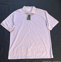 Front view of violet Nike polo T-shirt with tags, showing collared neck and Nike logo on left chest.
