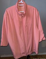 Front view of the pink women's jacket from Olsen Collection on hanger, showing zipper and chest pocket