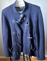 Front view of navy blue Ralph Lauren knit cardigan hanging on hanger, showing toggle fastenings and two pockets