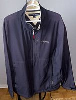 Front view of Tommy Hilfiger men's XL jacket hanging on a hanger, showing zipper, pockets, and logo detail.