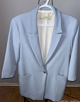 Full front view of light blue tailored women's jacket on hanger