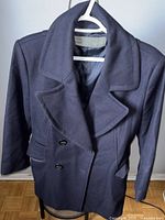Front view of navy blue Zara wool jacket on hanger showing double-breasted buttons and wide lapels.