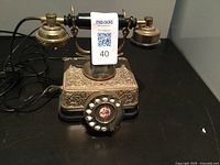 Front view of the antique dial telephone showing ornate metal base and rotary dial with black handset on cradle.