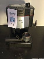 Front angled view of black and silver BRIEL Lido espresso coffee maker designed for espresso shots, with portafilter attached.