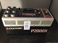 Front and side view of a Norman P2000X power supply unit with multiple connectors and control knobs.