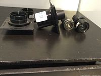 Photo showing four different photography lenses arranged on dark surface with different mounting styles.