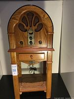 Front view of vintage style wooden radio cabinet with drawer and control knobs.