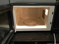 Open door showing beige interior and glass turntable of microwave.