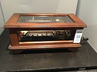 Full view of wooden case with glass top showing cylinder and comb mechanism, side crank visible