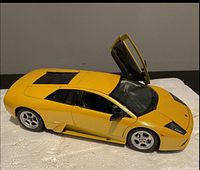 Yellow diecast Lamborghini toy car model with one door open, showing detailed interior and front hood slightly open.