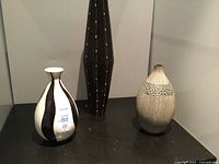 Photo showing three vases: two ceramic vases with different designs and one tall wooden vase with inlaid patterns.