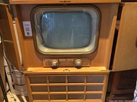 Front view of vintage General Electric console TV with wooden cabinet and closed front panel doors.