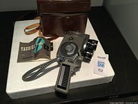 Yashica 8mm film camera with pistol grip and multiple lenses mounted on front, accompanied by carrying case and user manual.