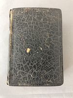 Front cover view showing worn black leather binding with cracking and scuffs.