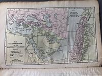 Photo of antique book page showing a colored map titled 'The Distribution of the Posterity of Noah' with geographic regions and biblical genealogical details.