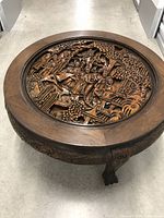 Full top view of round coffee table showing carved central scene and rim
