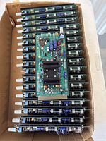 Seventeen Benchmark Media Systems amplifier circuit boards stacked inside a cardboard box, showing the side profile and components on the boards.