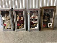 Four boxed holiday-themed animated and illuminated figures, standing in original packaging, holiday attire, holding candles