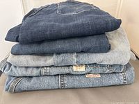 Stack of five folded Levi Strauss & Co. blue denim jeans showing a range of blue washes from dark to light.