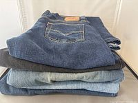 Five pairs of folded Levi's jeans stacked, showing various denim shades including blue and black