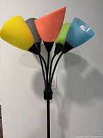 Close-up view of the five colored lamp shades showing yellow, orange, blue, green, and black shades attached to black stems.