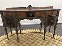 Front angle view of antique William & Mary style wooden desk with floral painted panels and carved legs.