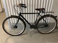 Side view of the green Raleigh bicycle showing full frame, rear rack, saddle, and front wheel.