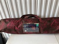 Brown carrying case with pink floral pattern for a butterfly chair, showing label with chair image and brand details.