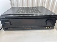 Front view of the Sony STR-G3 audio/video control center showing buttons, display, input jacks, and volume knob.