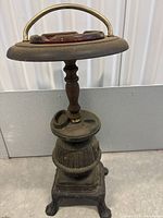 Side view of the Victorian ashtray stand showing cast iron base, wooden column, and ashtray top with brass handle.
