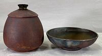 Photo showing the duo of pottery items: a covered jar and a shallow bowl, exhibiting their colors, textures, and shapes.