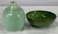 Pair of art pottery vase and bowl displayed side by side on white surface