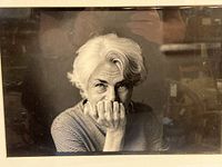 Close-up of the black and white photograph showing an elderly woman with white hair resting her chin on her hand, signed by photographer.