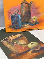 Close-up showing details and textures of two pastel paintings of still life with pottery and fruit in pastel medium.