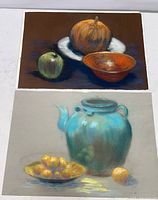 Photo of two pastel still life paintings by Richard Trost showing detailed compositions of fruit, bowls, and a teapot.