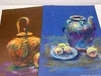 Both original pastel paintings seen together on a flat surface, showing still lifes with teapots and lemons.