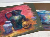 Two pastel still life paintings by Richard Trost, showing ceramic vessels and fruit compositions with vibrant backgrounds