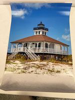 Photo of the rolled 20x30 inch original photograph of Port Boca Grande Lighthouse by Richard Trost, showing the lighthouse building on stilts with clear blue sky.