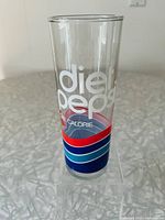 Tall clear glass with white Diet Pepsi lettering and blue, red, teal wave graphics on a countertop.